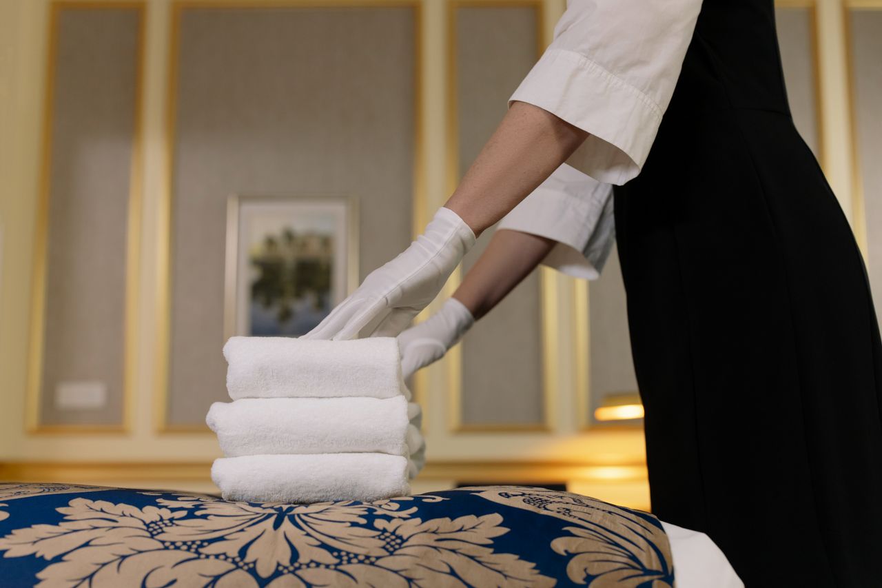 Une femme de chambre d’hôtel empile soigneusement des serviettes propres dans une chambre au cadre luxueux.